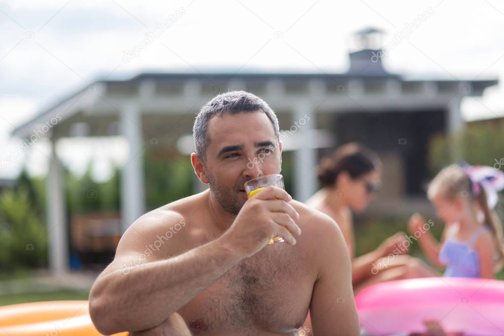 Man chilling near pool with his family at the weekend