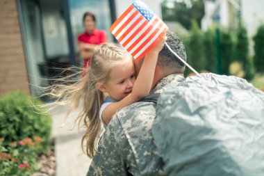 Kızı küçük Amerikan bayrağı tutan baba sıkı sarılma
