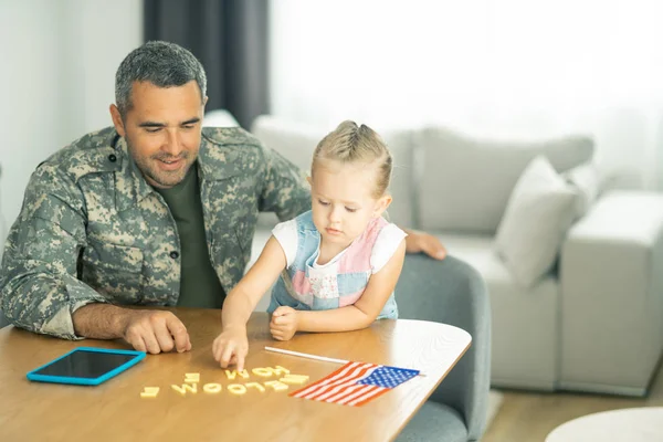 Meisje gastvrije papa dragen militair uniform thuis — Stockfoto