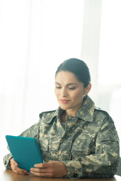 Female soldier holding tablet and chatting with her family