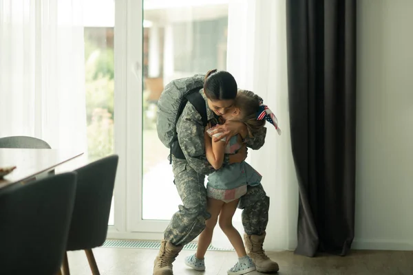 Mujer con uniforme militar abrazando a su hija — Foto de Stock