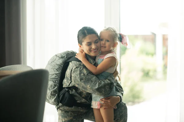 Militaire vrouw dragen rugzak knuffelen haar mooi meisje — Stockfoto