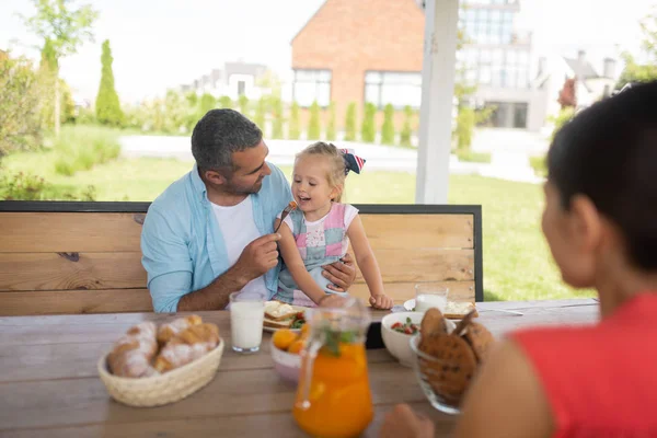 Papai alimentando sua filha enquanto desfruta de café da manhã fora — Fotografia de Stock