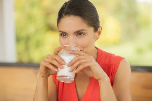Žena se cítí zamyšlená, když pije mléko k snídani — Stock fotografie