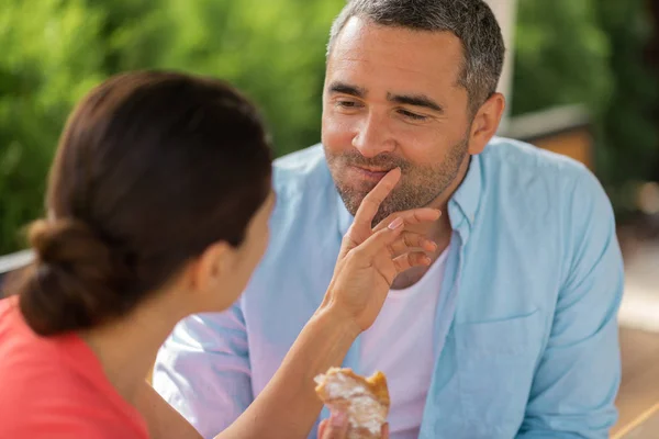 Hustru tar hand om maken medan utfodring honom med croissant — Stockfoto