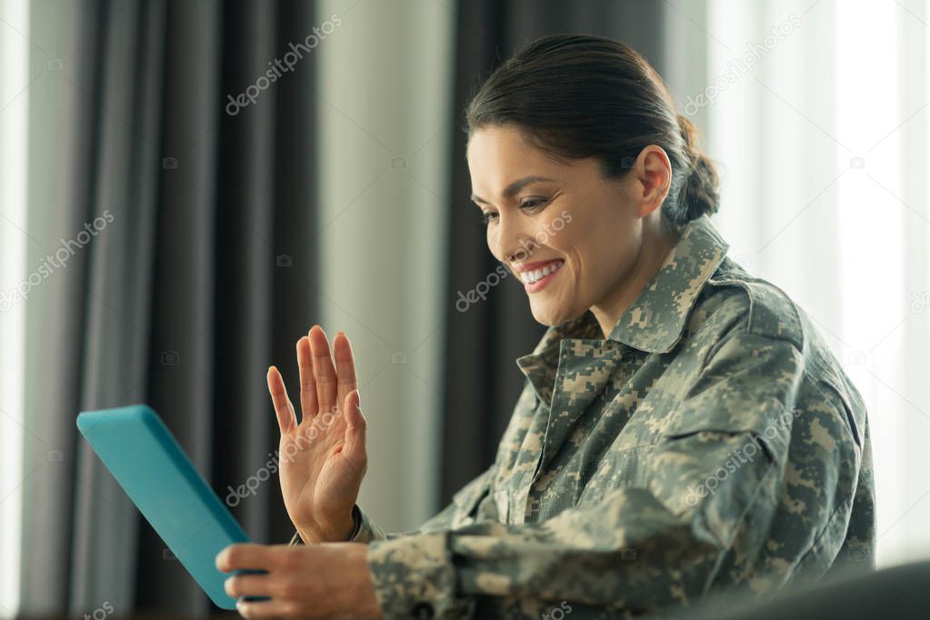 Beaming woman waving while having video chat with children