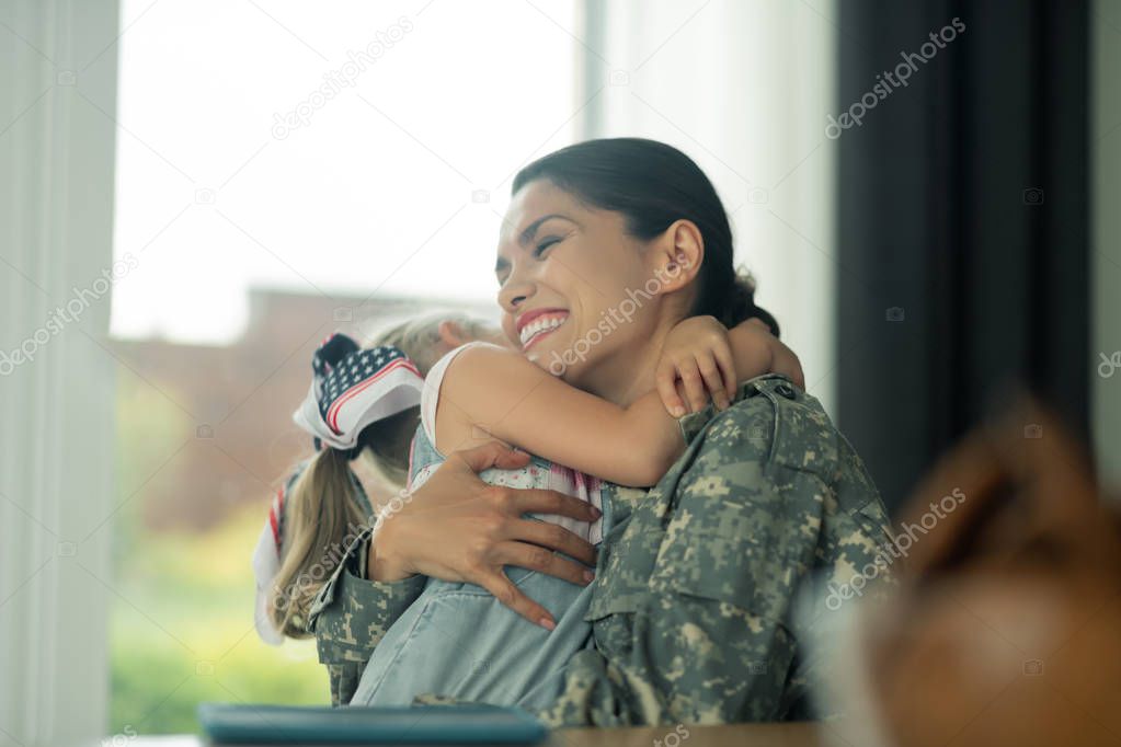 Military woman laughing while hugging her daughter