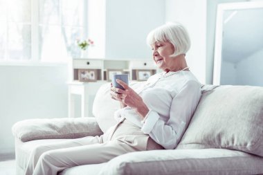 Şık emekli kadın rahat oturma odasında oturan çay fincan içme