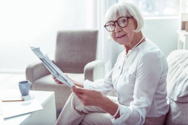 Hoş yaşlı bayan evde yerel haberleri okurken neşeli hissediyorum