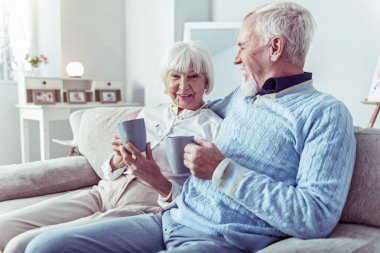 Sevecen sevgi dolu emekli adam kanepede oturan onun sevimli zarif karısı sarılma