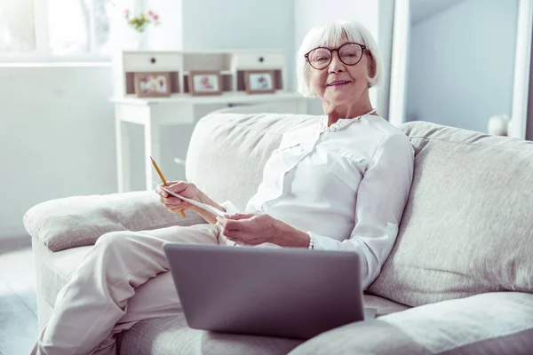 Femme retraitée portant des lunettes regardant la vidéo sur son ordinateur portable — Photo