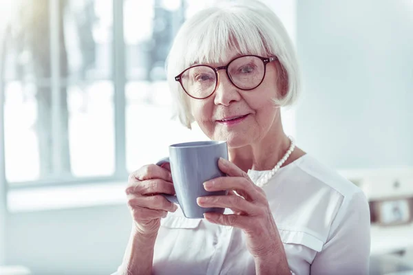 Elegante hermosa mujer jubilada sosteniendo la taza azul con té caliente — Foto de Stock