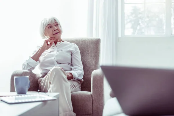 Elegante mujer jubilada sentada en sillón de pie cerca de la ventana — Foto de Stock