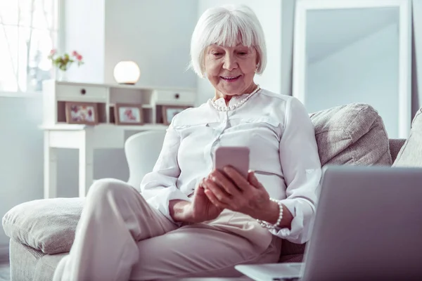 Elegant stylish grandmother typing message to her grandchildren