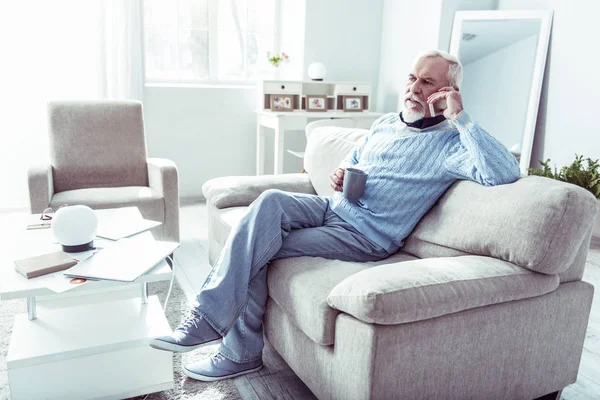 Elegante hombre retirado sosteniendo su teléfono mientras llama a su esposa desde casa — Foto de Stock