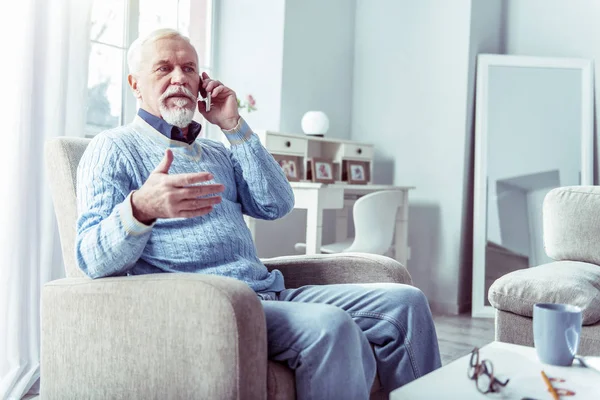 Elderly working businessman feeling busy calling his partners from home
