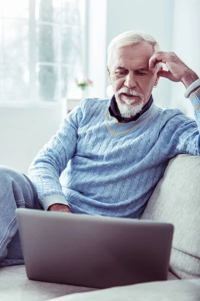 Стильный бородатый пенсионер в синем свитере с серебряным ноутбуком — стоковое фото