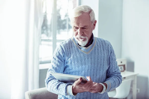 Бородатый седой мужчина с серебряным ноутбуком, смотрящий фотографии — стоковое фото