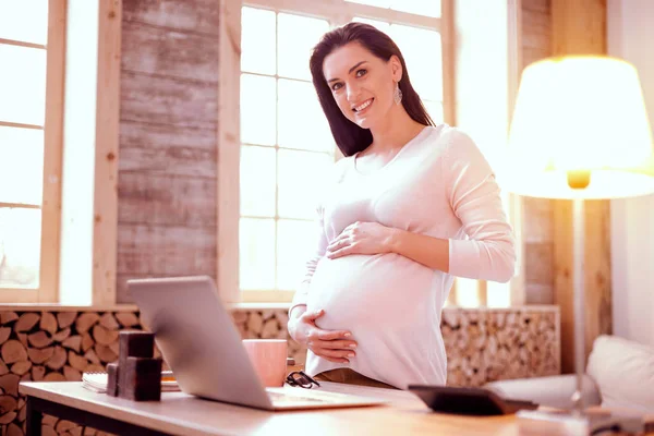 Charmante brünette Frau demonstriert ihre glückliche Schwangerschaft — Stockfoto