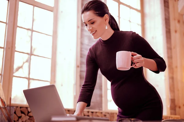 Embarazo joven atento que trabaja en su computadora portátil — Foto de Stock