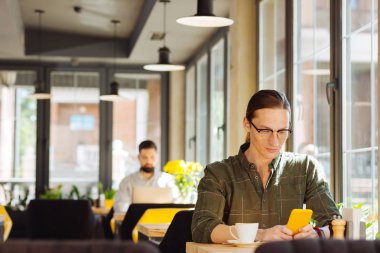 Bağlı kalmak. Arkadaşından mesaj alırken akıllı telefon ekranına bakan ciddi yakışıklı adam
