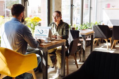 Hoş bir iletişim. Konuşurken dizüstü bilgisayarları ile karşı karşıya oturan hoş erkekler
