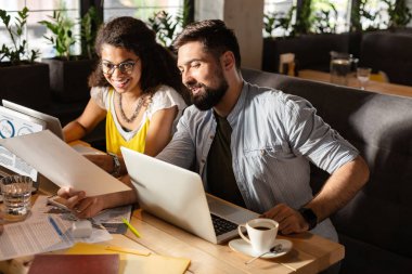 Modern işyeri. Güzel akıllı insanlar dizüstü bilgisayarlar üzerinde çalışırken birbirleriyle konuşurken