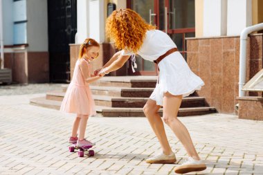 Birlikte zaman. Mutlu kız kaykay üzerinde dururken yüzünde gülümseme tutmak