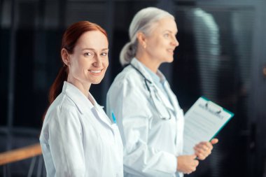 Sağlık sigortası sertifikası. Sağlık sigortası sertifikası ile meslektaşının yanında duran mutlu bir genç kadın doktorun bel-up