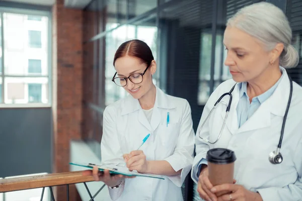 Clipboard Grey Haired Woman White Coat Looking Her Smiling Young — Stock Photo, Image