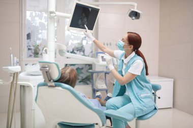 Girl looking at the screen while dentist making X-ray clipart