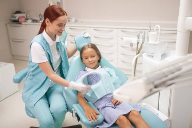 Kızıl saçlı çocuk diş hekimi sevimli kız öğrenci ayna veren