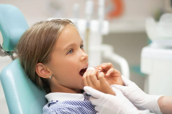 Dentista usando guantes blancos ayudando a la chica a poner protector bucal — Foto de Stock