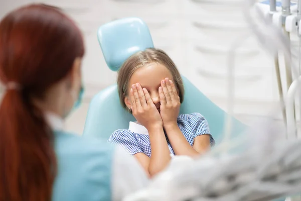 Liten flicka som stänger ögonen medan du känner dig rädd för tandläkare — Stockfoto