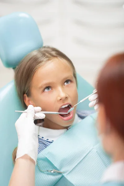 白い手袋を着た子供の歯科医は女の子を調べる — ストック写真