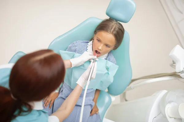 Rothaarige Kinderzahnärztin untersucht attraktives Mädchen — Stockfoto