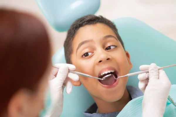 Przystojny ciemny Skinned chłopiec odwiedzając biuro dentysta do leczenia zębów — Zdjęcie stockowe