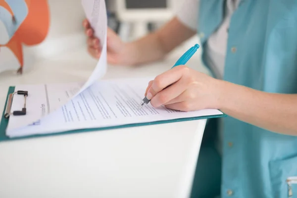 Gros plan du dentiste portant l'uniforme écrivant quelques recommandations — Photo