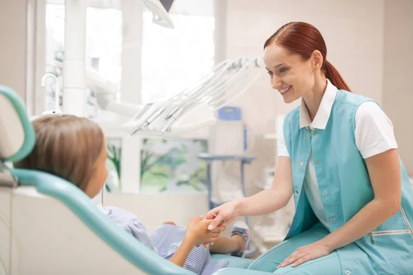 Rothaarige Zahnärztin lächelt und schüttelt ihrem Klienten die Hand — Stockfoto