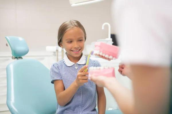 Fröhliches schönes Mädchen lächelt, während es die Zahnbürste hält — Stockfoto