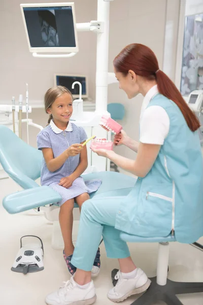 Barn tandläkare bär uniform Teaching Girl att borsta tänderna — Stockfoto