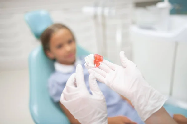 Dziecko dentysta ubrany w białe rękawice trzymanie Straż nocna — Zdjęcie stockowe