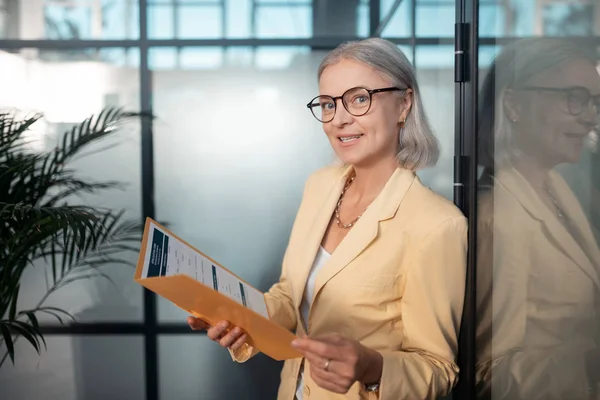 Mujer de negocios agradable en gafas con una carpeta de papel — Foto de Stock