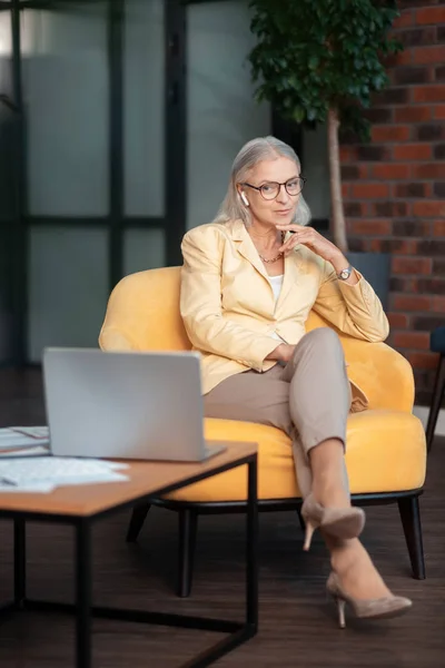 Красивая стильная предпринимательница, сидящая в удобном желтом кресле — стоковое фото