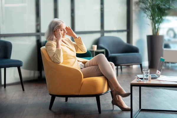 Старшая деловая женщина, страдающая головной болью в офисе — стоковое фото