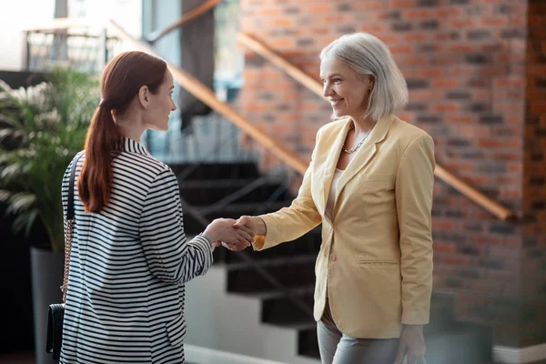 Joven empresaria contenta saludando a su colega senior — Foto de Stock