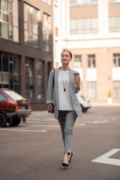 Confident stylish young woman walking along the street