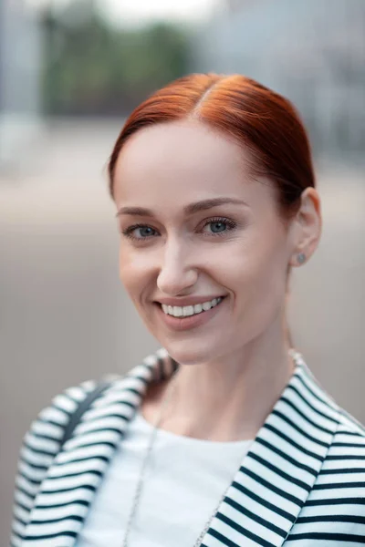 Sonriente hermosa mujer joven de ojos azules pelirroja de pie al aire libre — Foto de Stock