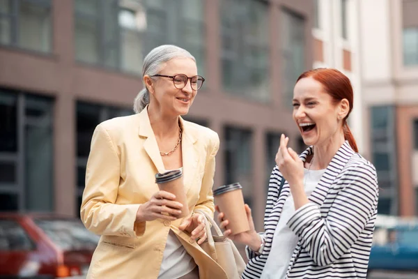 Dos felices damas de negocios modernas y atractivas riendo al aire libre — Foto de Stock