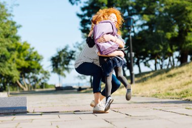 Güzel genç anne okuldan önce çocuğunu kucaklayan